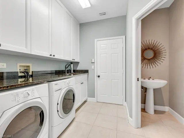 Clothes washing area featuring cabinets, light tile patterned flooring, sink, and independent washer and dryer