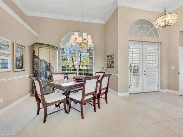 Dining room with an inviting chandelier, light tile patterned floors, crown molding, and french doors