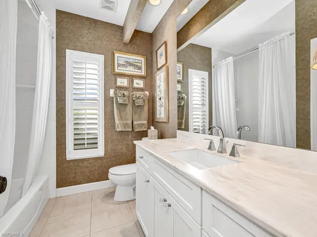 Full bathroom with plenty of natural light, tile patterned floors, beam ceiling, and toilet