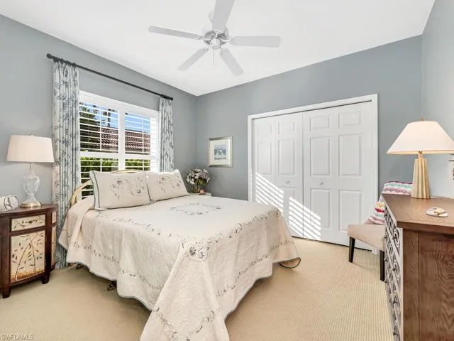 Carpeted bedroom featuring ceiling fan and a closet