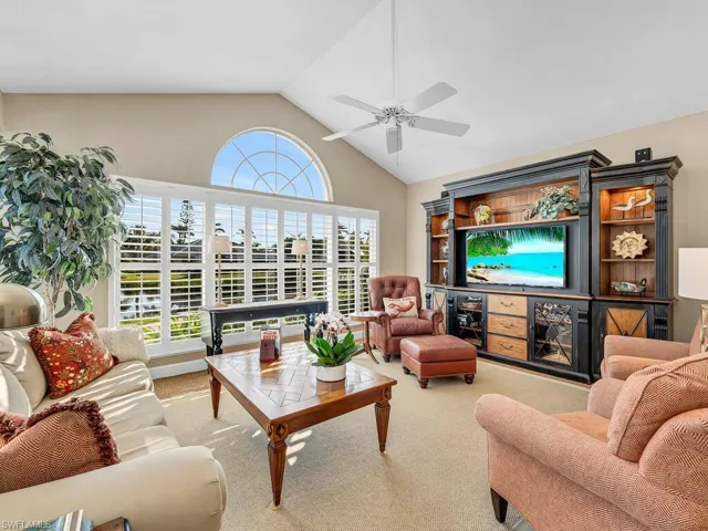 Living room featuring ceiling fan, high vaulted ceiling, and light carpet