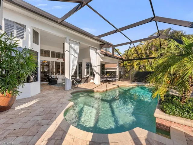 View of swimming pool with glass enclosure and a patio area