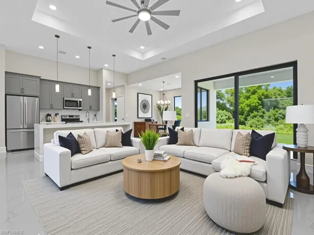 Living room featuring light marble finish flooring, recessed lighting, a raised ceiling, a ceiling fan, and a towering ceiling