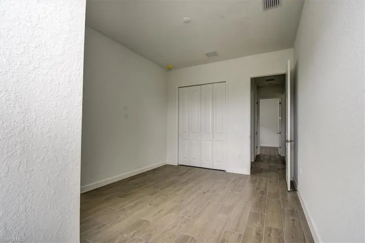 Unfurnished bedroom with wood finish floors, a textured wall, and a closet