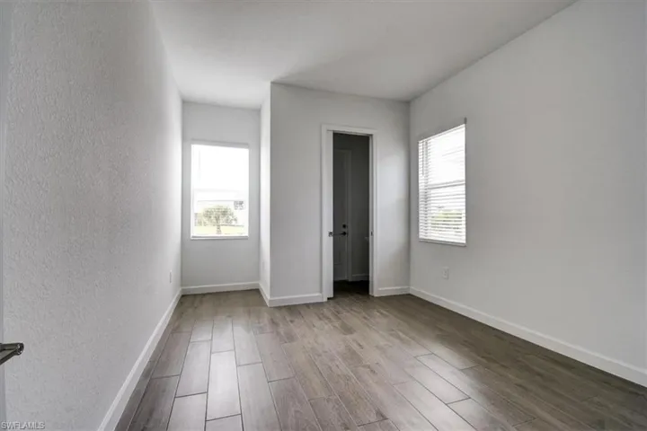 Unfurnished bedroom featuring wood finished floors, multiple windows, and a textured wall