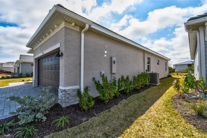 View of side of property with stucco siding, stone siding, and a lawn