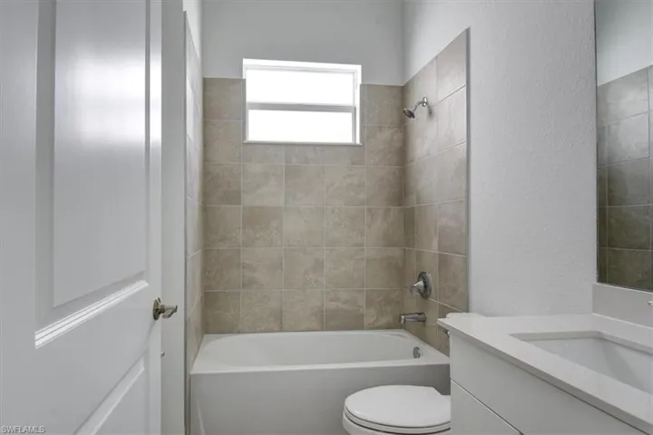 Full bath featuring a textured wall, shower / bathtub combination, and vanity