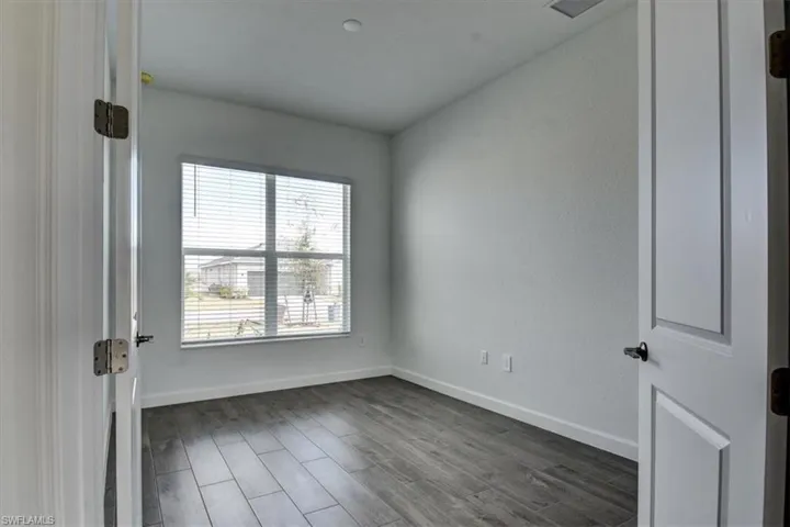 Empty room with dark wood-style flooring and baseboards