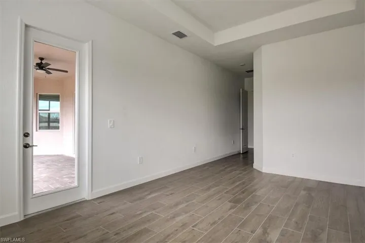 Spare room featuring a raised ceiling, wood finish floors, and a ceiling fan