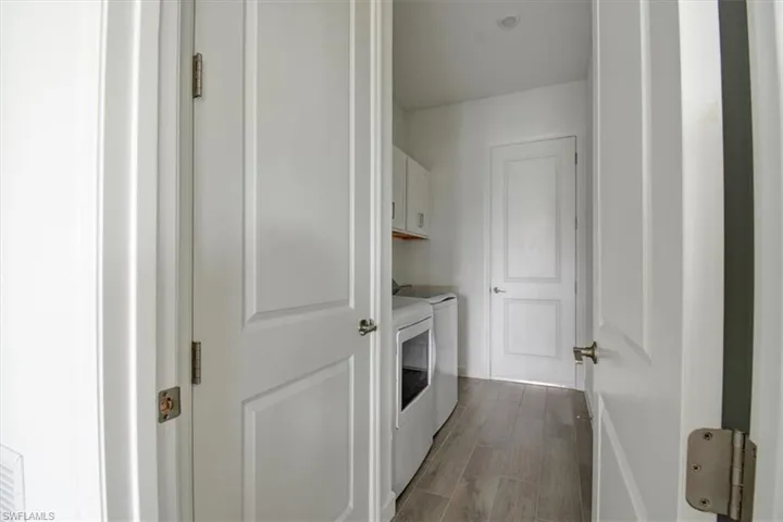 Laundry room featuring dark wood-style floors, cabinet space, and washer and dryer