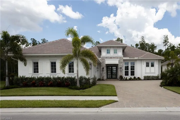View of front of house featuring french doors, stone siding, a front lawn, driveway, and stucco siding