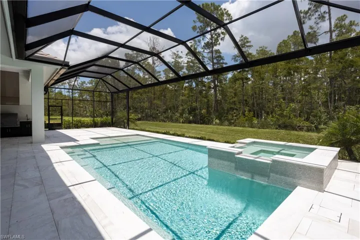 View of pool with a pool with connected hot tub, a patio, a lawn, and glass enclosure