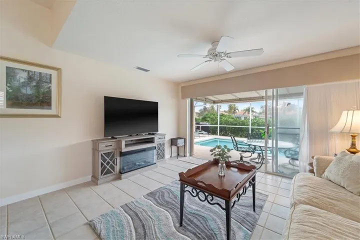 Living area with light tile patterned flooring, ceiling fan, and a sunroom