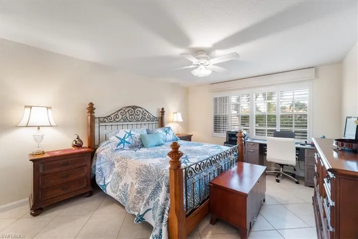 Bedroom with light tile patterned floors, ceiling fan, and a desk