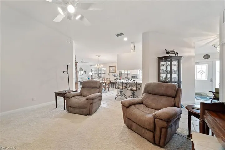 Living room with light carpet, ceiling fan, light tile patterned floors, and recessed lighting