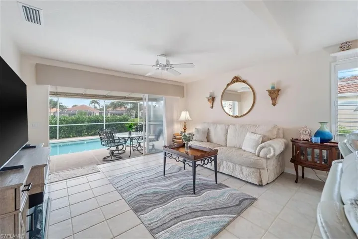 Living room with a sunroom, light tile patterned floors, and a ceiling fan
