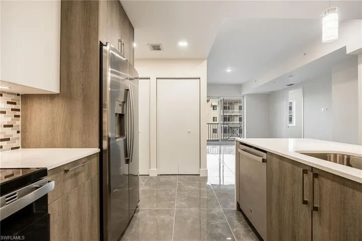 Kitchen featuring decorative backsplash, light countertops, visible vents, modern cabinets, and stainless steel appliances