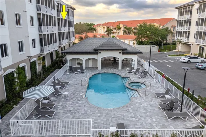 Pool at dusk featuring a community hot tub, fence, and a patio area