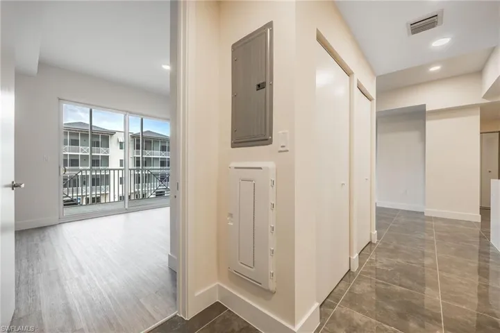 Hallway featuring electric panel, baseboards, visible vents, and recessed lighting