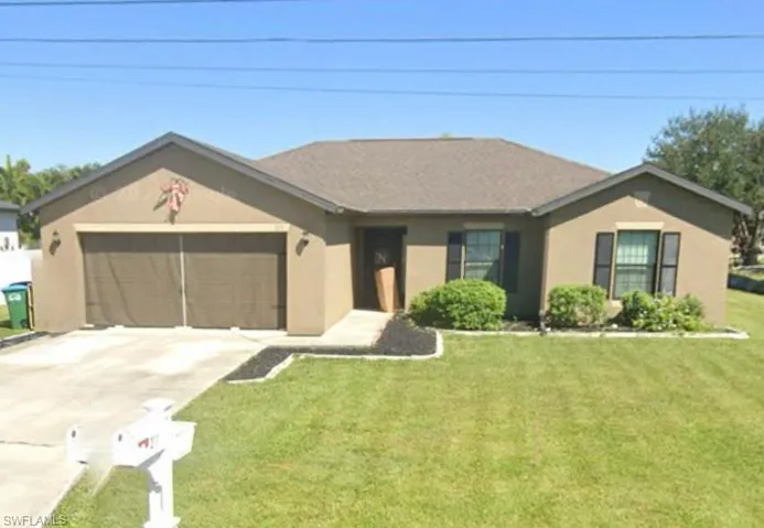 Ranch-style house with driveway, stucco siding, an attached garage, and a front lawn