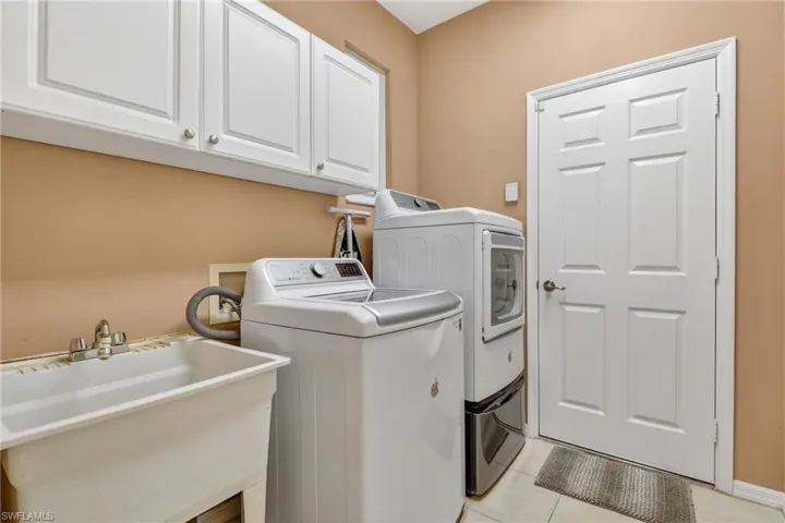 Laundry area featuring washing machine and dryer, cabinet space, and light tile patterned floors