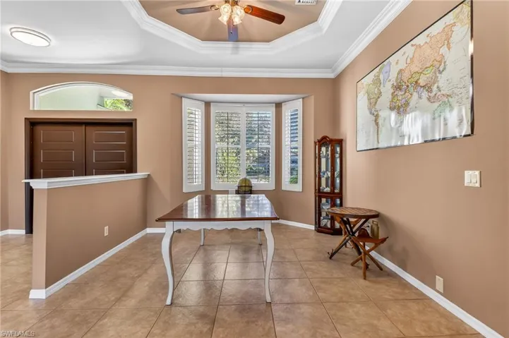 Office with ornamental molding, a ceiling fan, light tile patterned flooring, and a raised ceiling