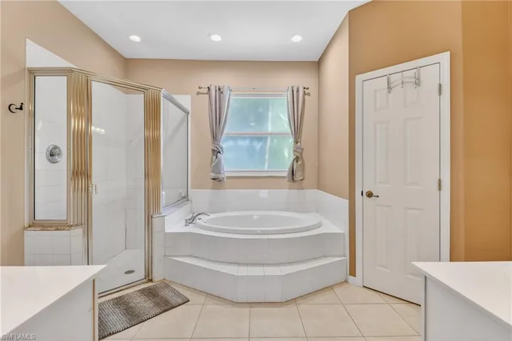 Full bathroom with vanity, a stall shower, a bath, light tile patterned floors, and recessed lighting