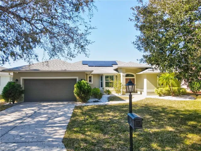 Ranch-style house featuring solar panels, a front yard, a garage, and stucco siding