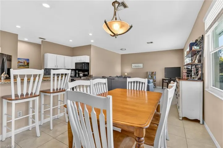 Dining area with light tile patterned floors and recessed lighting