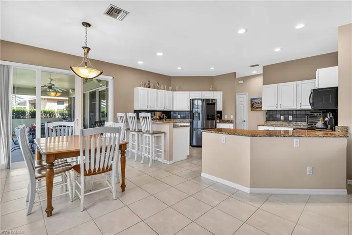 Kitchen with a peninsula, decorative backsplash, a kitchen breakfast bar, and dark stone countertops