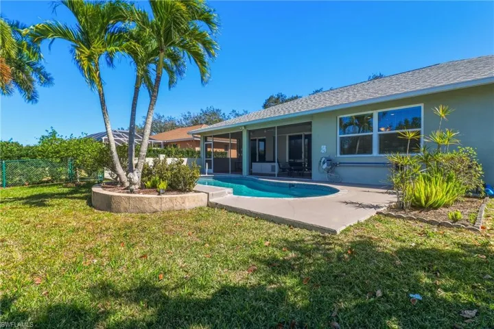 Rear view of property featuring a sunroom, stucco siding, a shingled roof, and a patio area