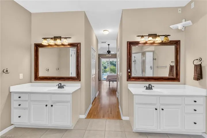 Bathroom featuring two vanities, light tile patterned floors, and a ceiling fan