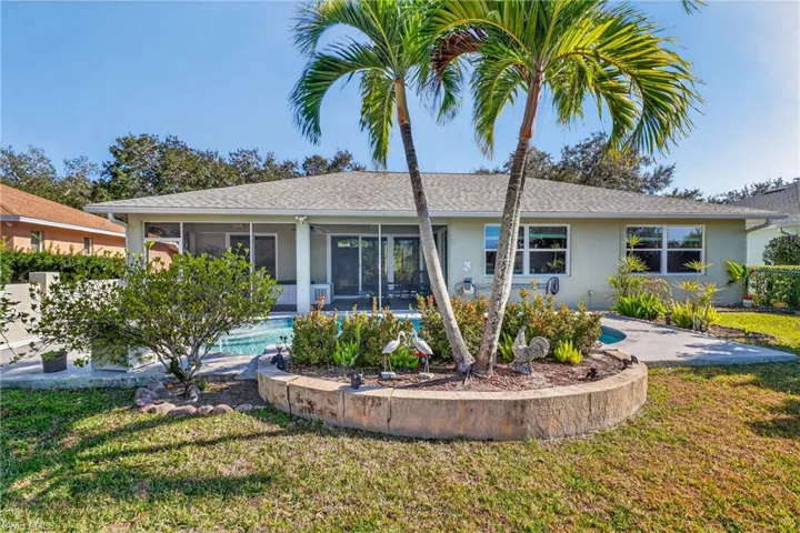 Rear view of property with a yard, stucco siding, a sunroom, an outdoor pool, and roof with shingles