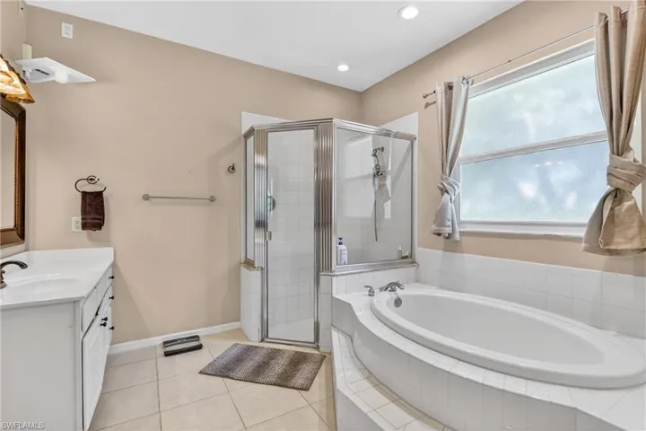 Full bathroom with vanity, a stall shower, a garden tub, light tile patterned floors, and recessed lighting