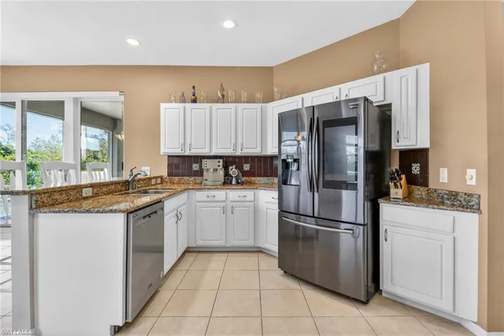 Kitchen with dark stone countertops, stainless steel appliances, white cabinetry, a peninsula, and recessed lighting