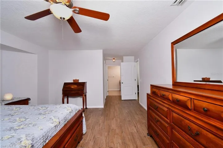 Bedroom with dark wood-style flooring, a textured ceiling, and a ceiling fan