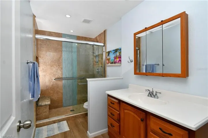 Full guest bath featuring vanity, a stall shower, and light wood finished floors