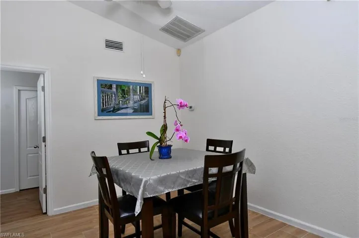 Dining area with lofted ceiling, light wood-style floors, and a textured wall