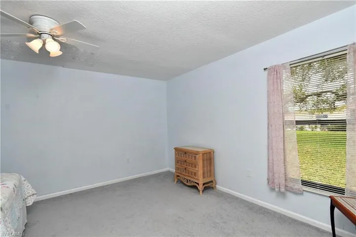 Unfurnished bedroom featuring a ceiling fan, a textured ceiling, and light colored carpet
