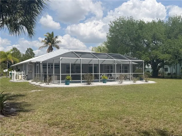Back of property with glass enclosure, a yard, a sunroom, a pool, and a patio area