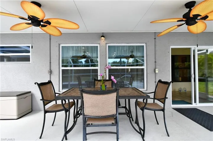 Outdoor covered lanai with ceiling fan, outdoor dining area, and a patio area