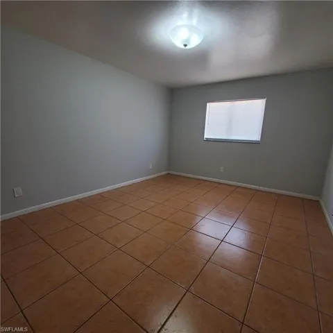 Empty room featuring light tile patterned floors and baseboards