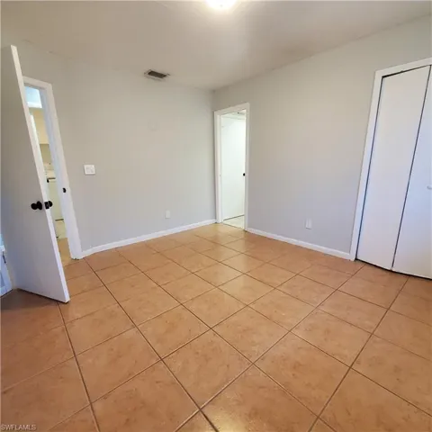Empty room with light tile patterned flooring and baseboards