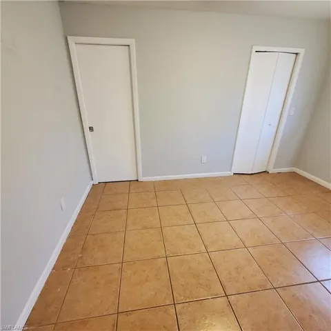 Unfurnished bedroom with baseboards and light tile patterned floors