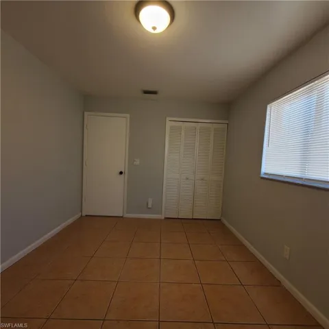 Unfurnished bedroom featuring light tile patterned floors and a closet