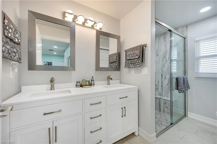 Bathroom with a marble finish shower and double vanity