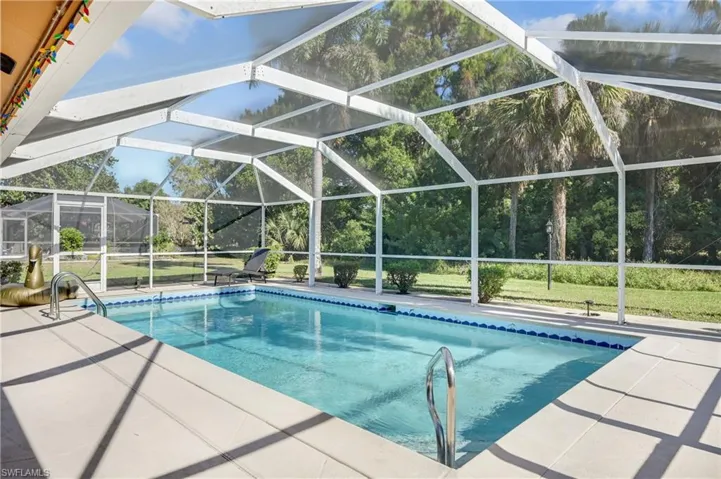 Swimming pool featuring a lanai, a sunroom, a patio, and view of scattered trees