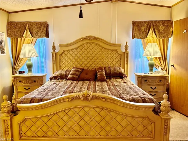 Carpeted bedroom featuring crown molding and a textured ceiling