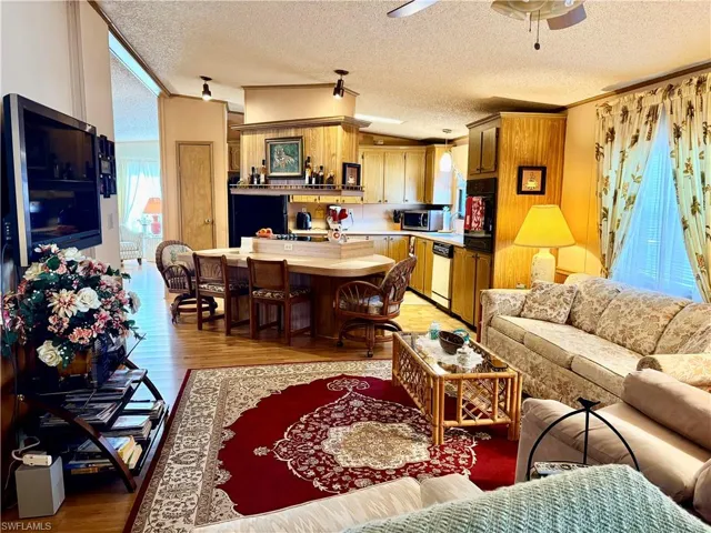 Living room featuring light wood-style floors, a textured ceiling, ceiling fan, and crown molding