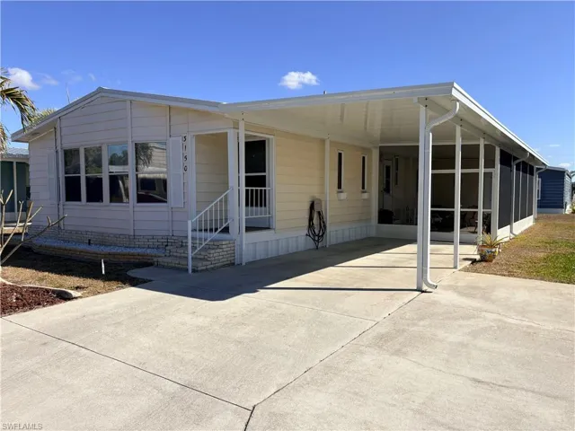 Manufactured / mobile home featuring an attached carport, concrete driveway, a patio, a sunroom, and entry steps